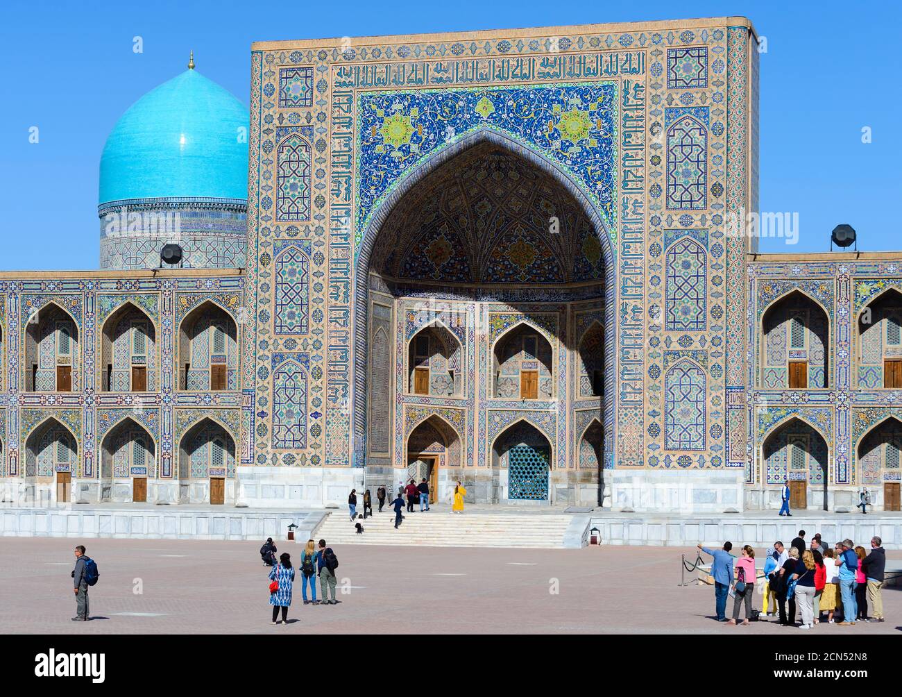 Touristes visitant le Registan à Samarkand avec Tilya-Kori Madrasa (madrassah) derrière. Tourisme en Ouzbékistan. Visiteurs du groupe. Banque D'Images