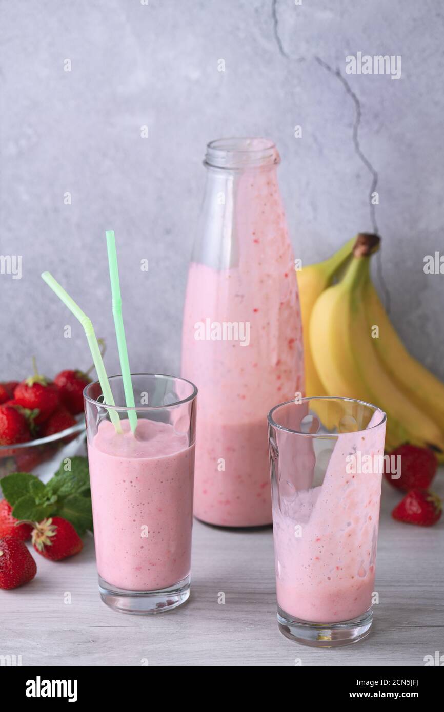 Prenez une boisson pour verser le smoothie banane-fraise fraîchement préparé Banque D'Images