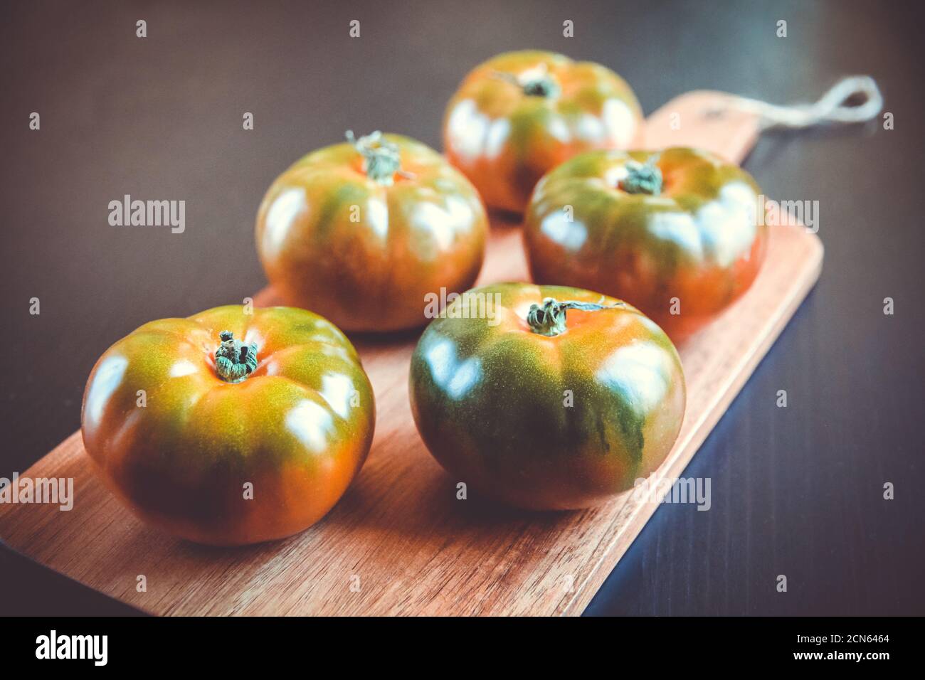 Tomates biologiques noires sur une planche à découper Banque D'Images