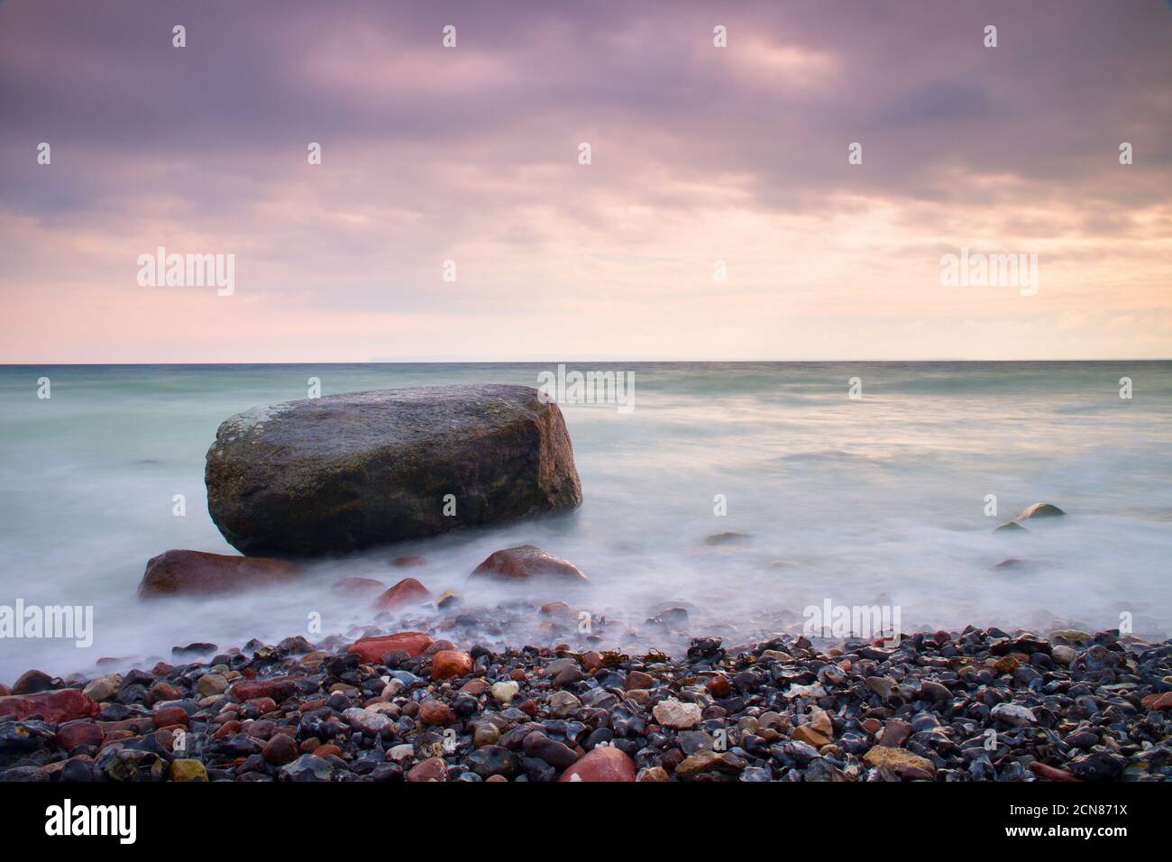 Ambiance romantique dans une matinée paisible en mer. De gros blocs qui sortent d'une mer ondulée et lisse. Horizon rose Banque D'Images