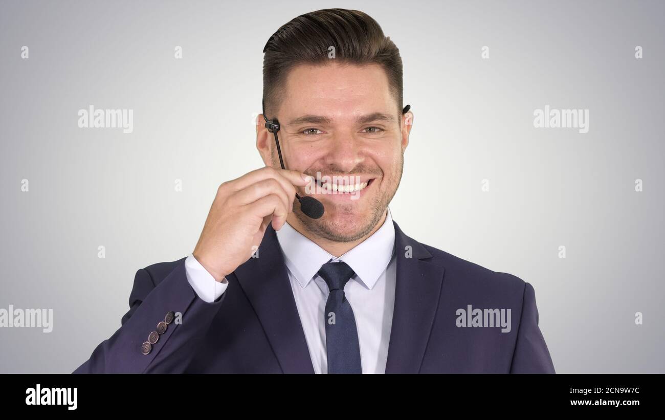 Un homme d'affaires charmant avec un micro-casque qui regarde dans l'appareil photo et le smilin Banque D'Images
