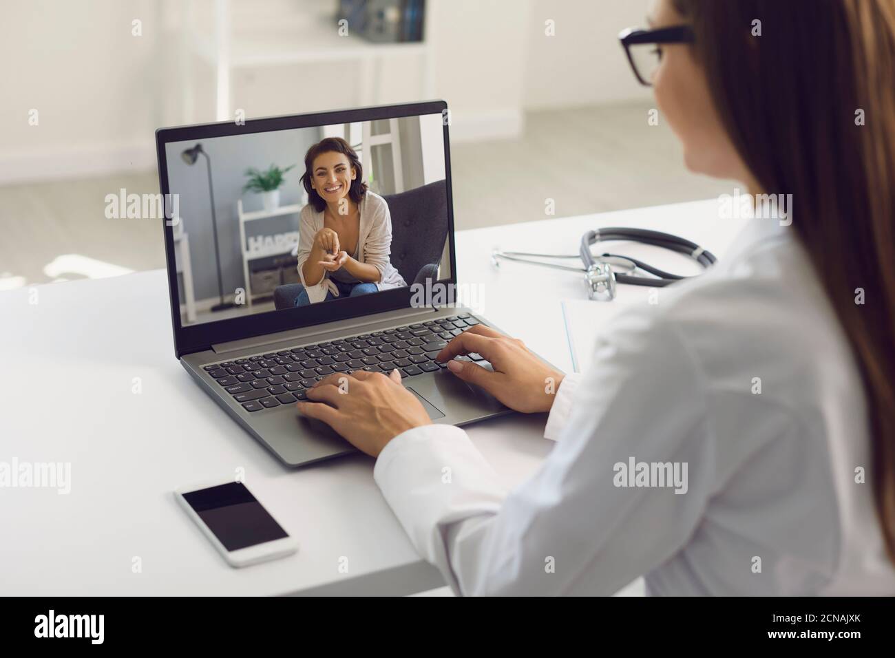 Appel vidéo vers un médecin en ligne. La patiente utilise l'application Web de la clinique médicale a un ordinateur portable qui parle au médecin à la maison. Banque D'Images