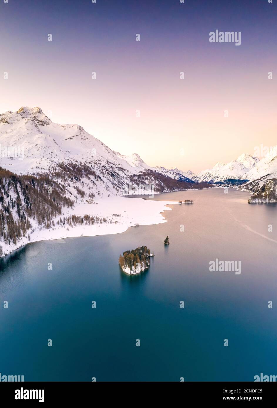 Aérien par drone du lac Sils entouré de sommets enneigés pendant un lever de soleil d'hiver, Engadine, canton de Graubunden, Suisse, Europe Banque D'Images