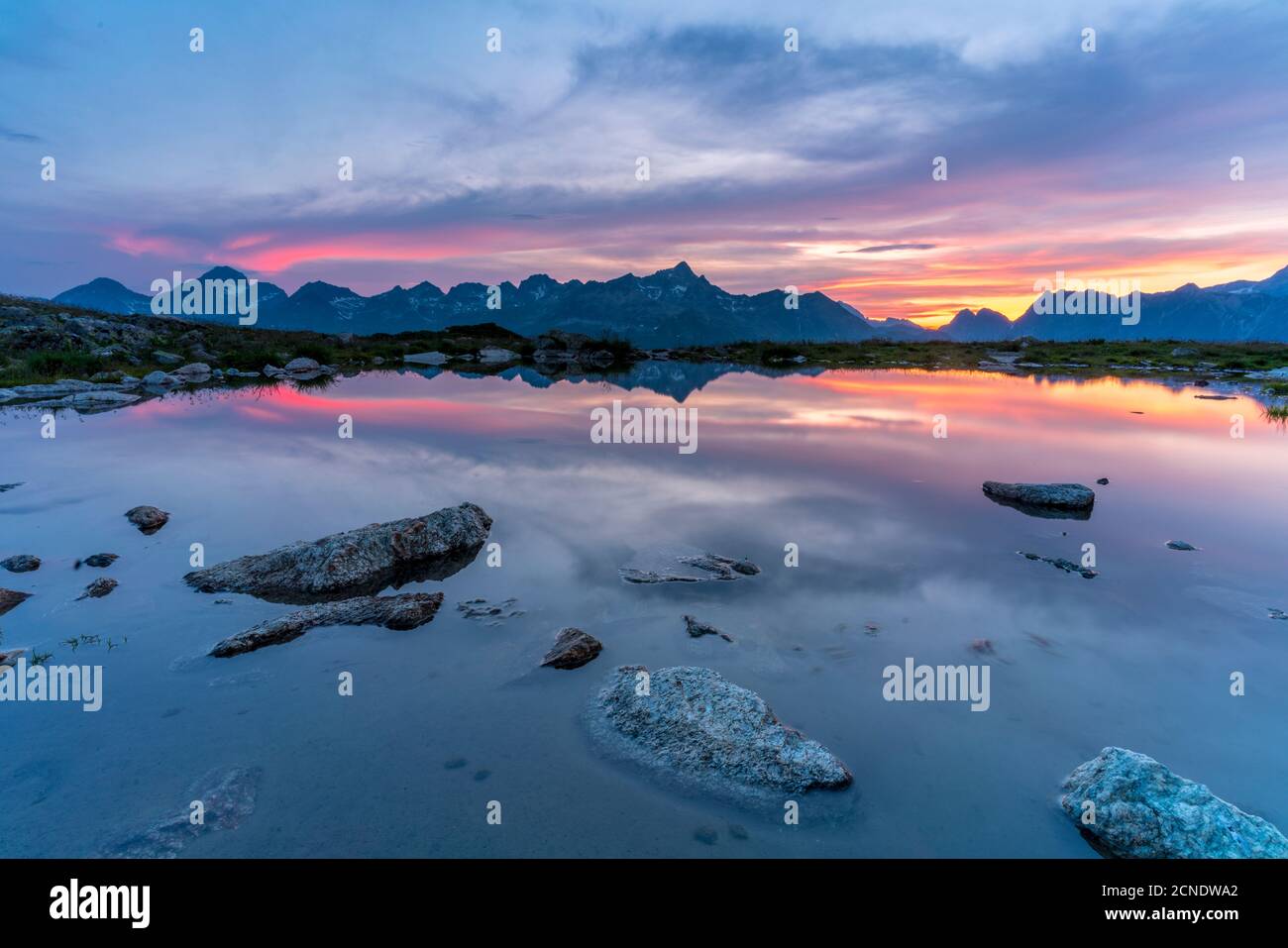 Ciel brûlant au coucher du soleil sur les montagnes se reflète dans le lac immaculé, Muottas Muragl, Engadine, canton de Graubunden, Suisse, Europe Banque D'Images