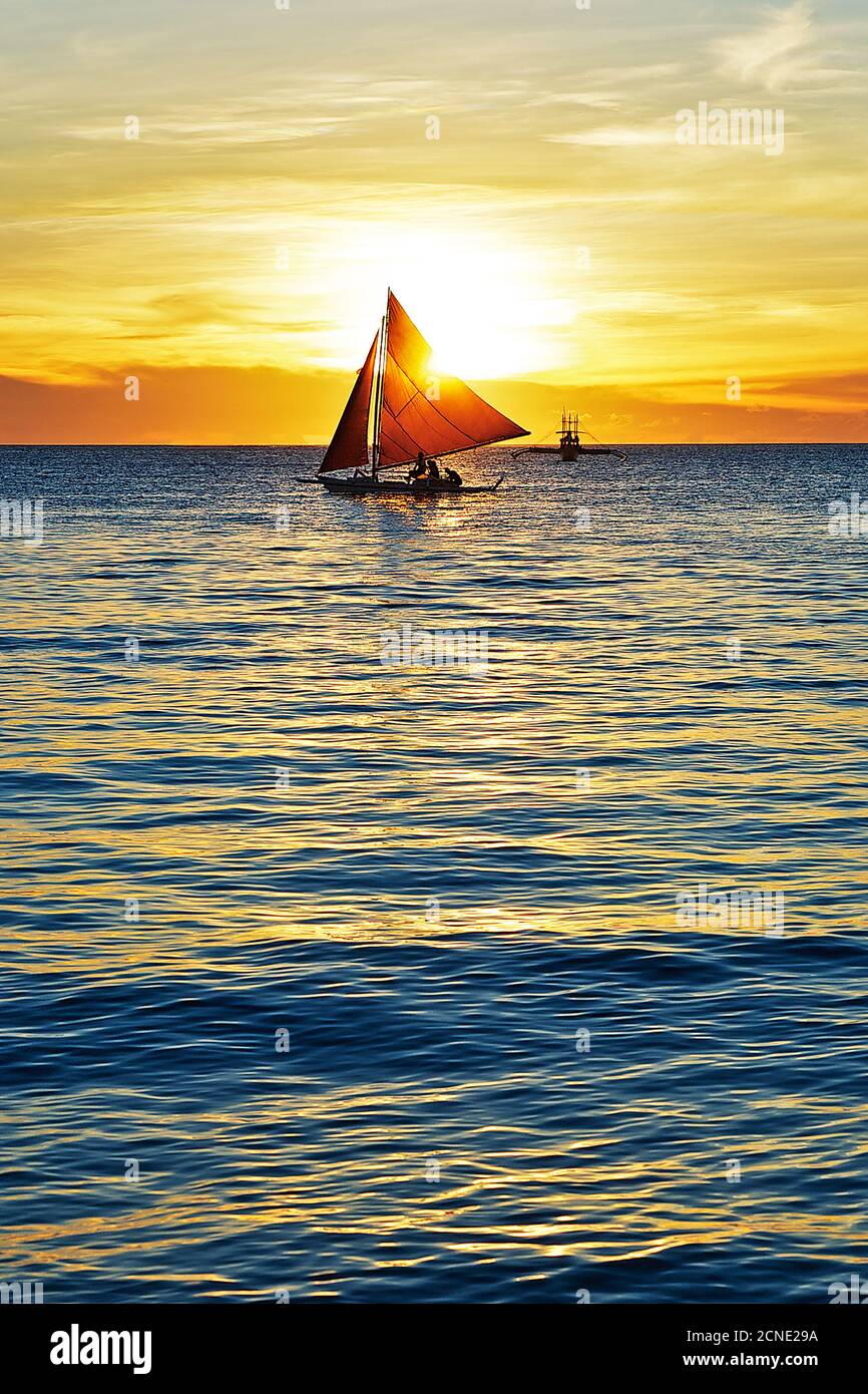 Vue idyllique d'un bateau à voile au coucher du soleil pittoresque avec des reflets dorés dans la mer, plage blanche de l'île Boracay, Aklan, Philippines Banque D'Images