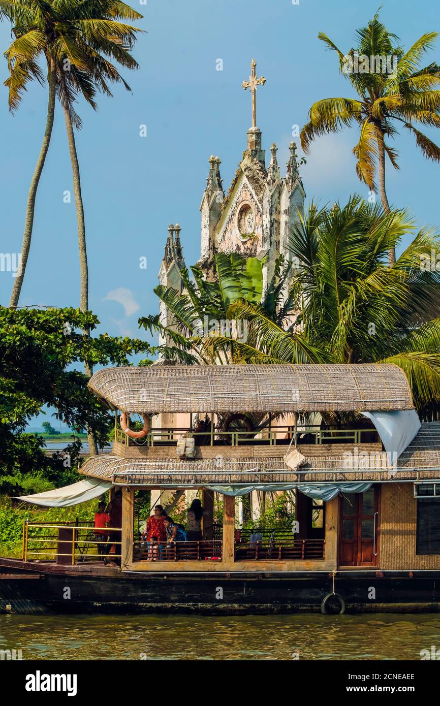 Vieille église avec façade patinée et péniche amarrée sur un arrêt de croisière dans les eaux profondes, Alappuzha (Alleppey), Kerala, Inde, Asie Banque D'Images