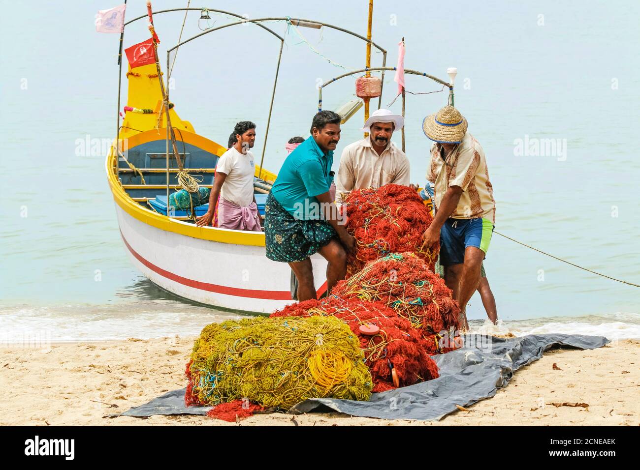 Pêcheurs transportant des filets lourds sur la rive à la populaire plage de Marari, Mararikulam, Alappuzha (Alleppey), Kerala, Inde, Asie Banque D'Images