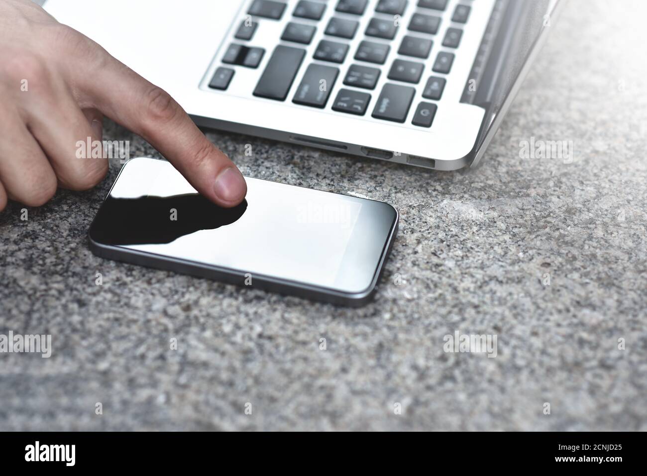 Image rognée d'un homme d'affaires avec un ordinateur portable dans la rue envoyant des messages texte à un collègue. Banque D'Images