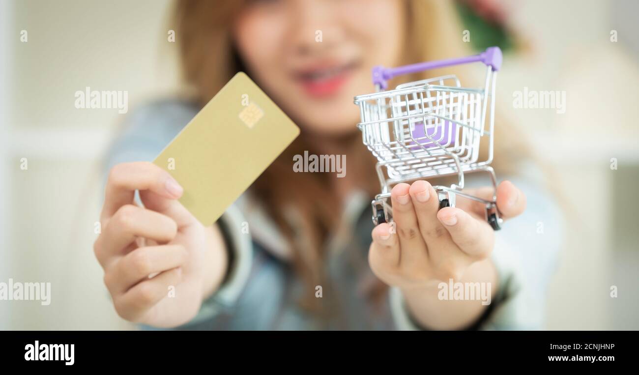 Beautiful woman holding credit card à la maison et penser à des magasins Les magasins en ligne. Concept de modernisation de magasinage en ligne. Banque D'Images