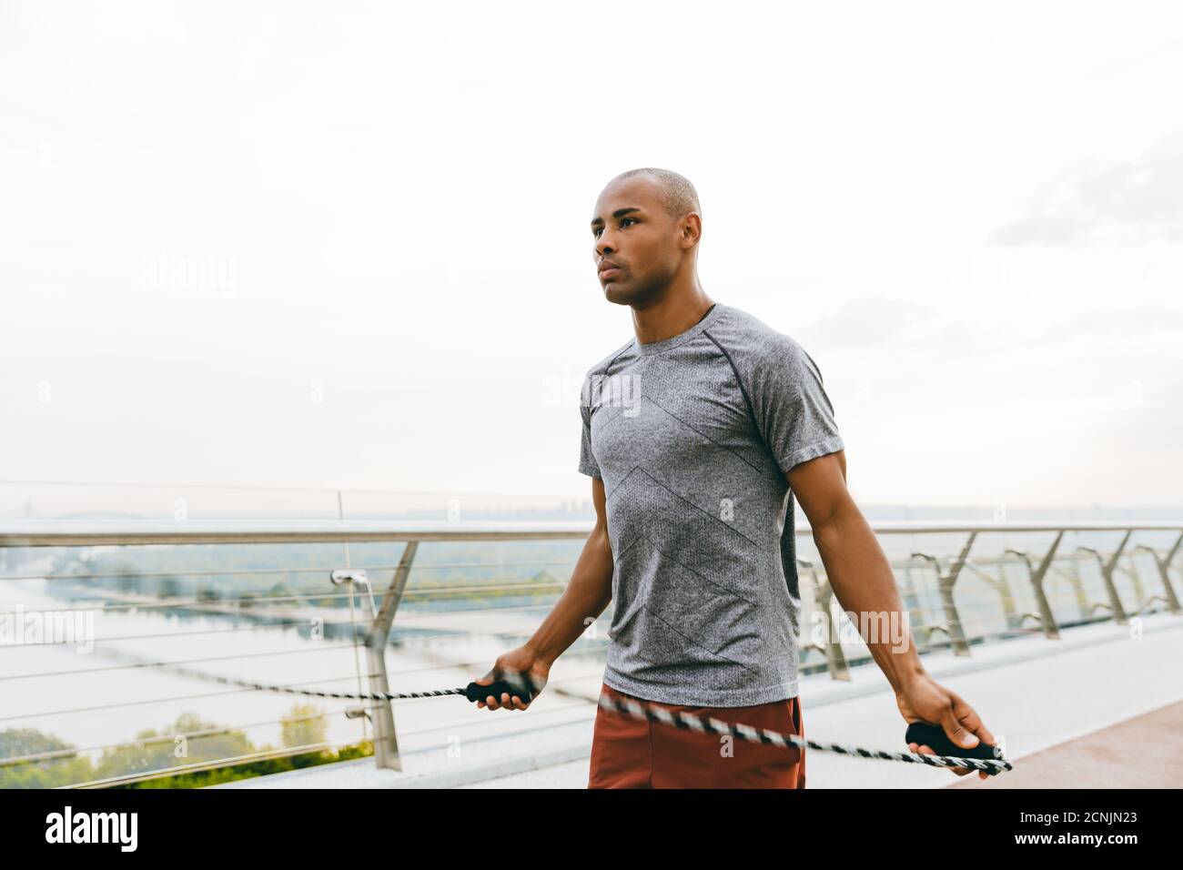 Beau sportif africain en uniforme de sport qui se réchauffe, sautant avec une corde Banque D'Images