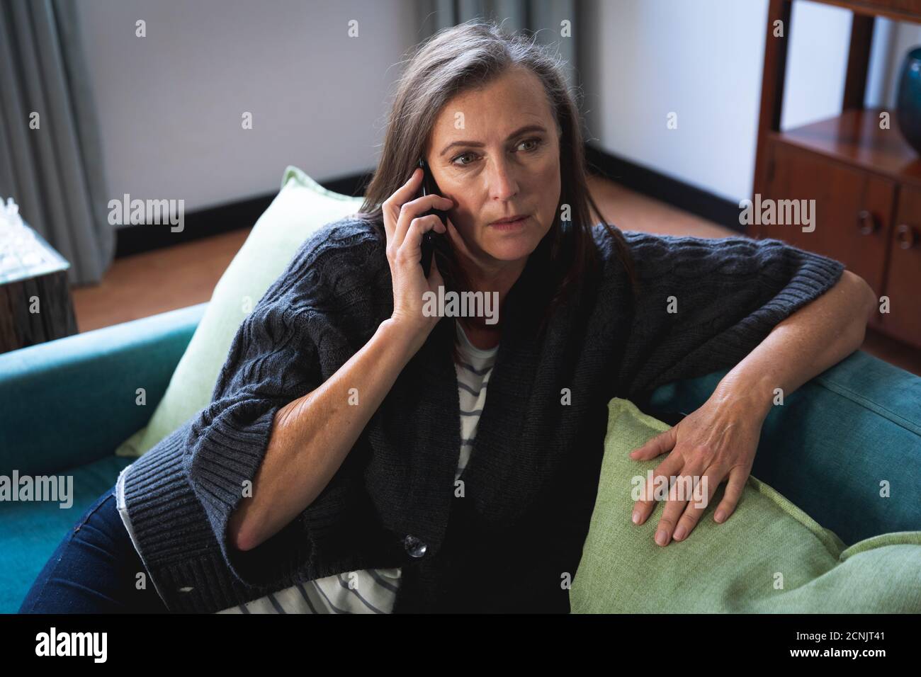 Femme caucasienne appréciant du temps à la maison, distanciation sociale et auto-isolement en quarantaine, assis sur un canapé dans le salon, parlant sur le ph Banque D'Images