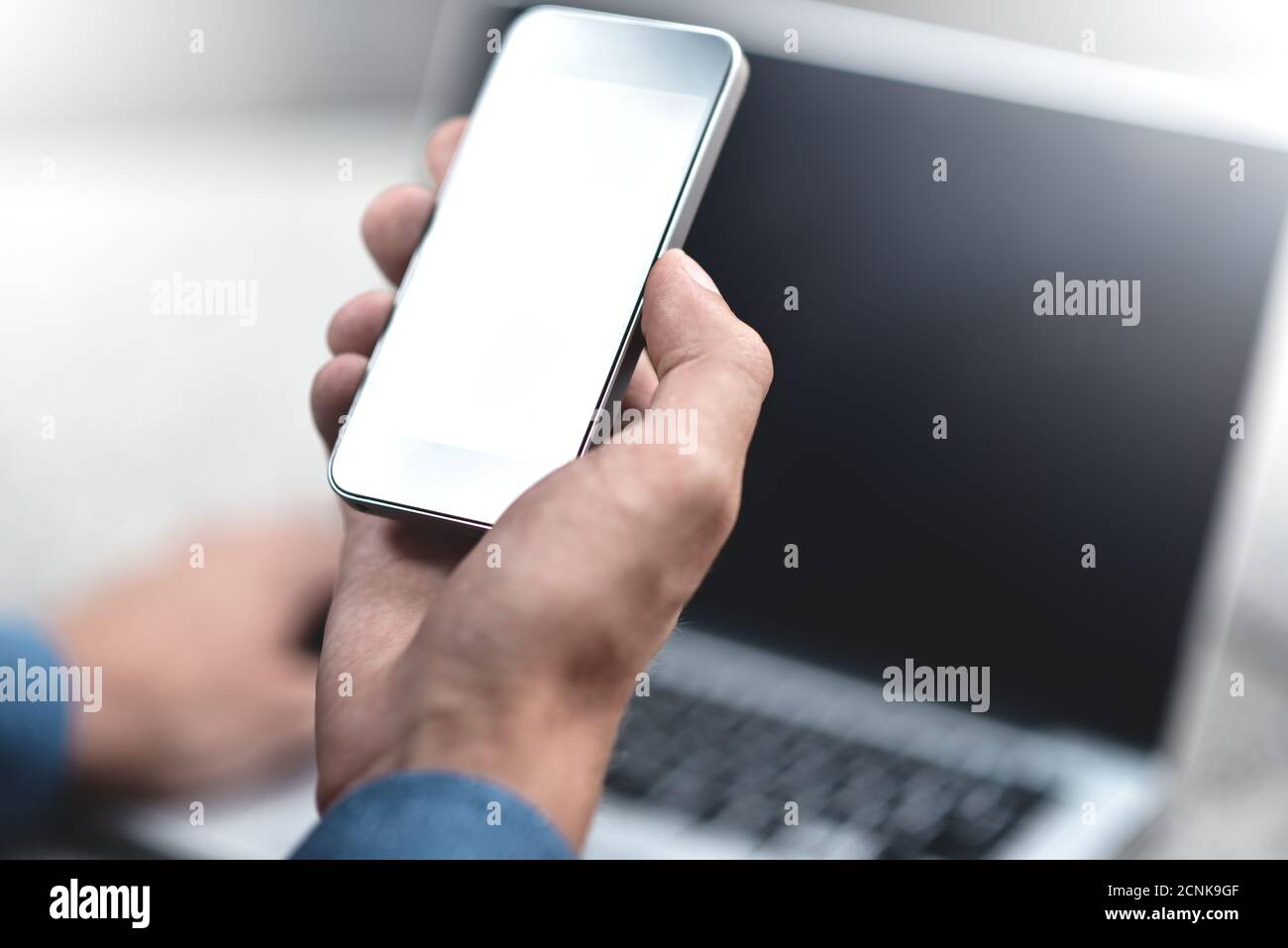 Image rognée d'un homme d'affaires avec un ordinateur portable dans la rue envoyant des messages texte à un collègue. Banque D'Images
