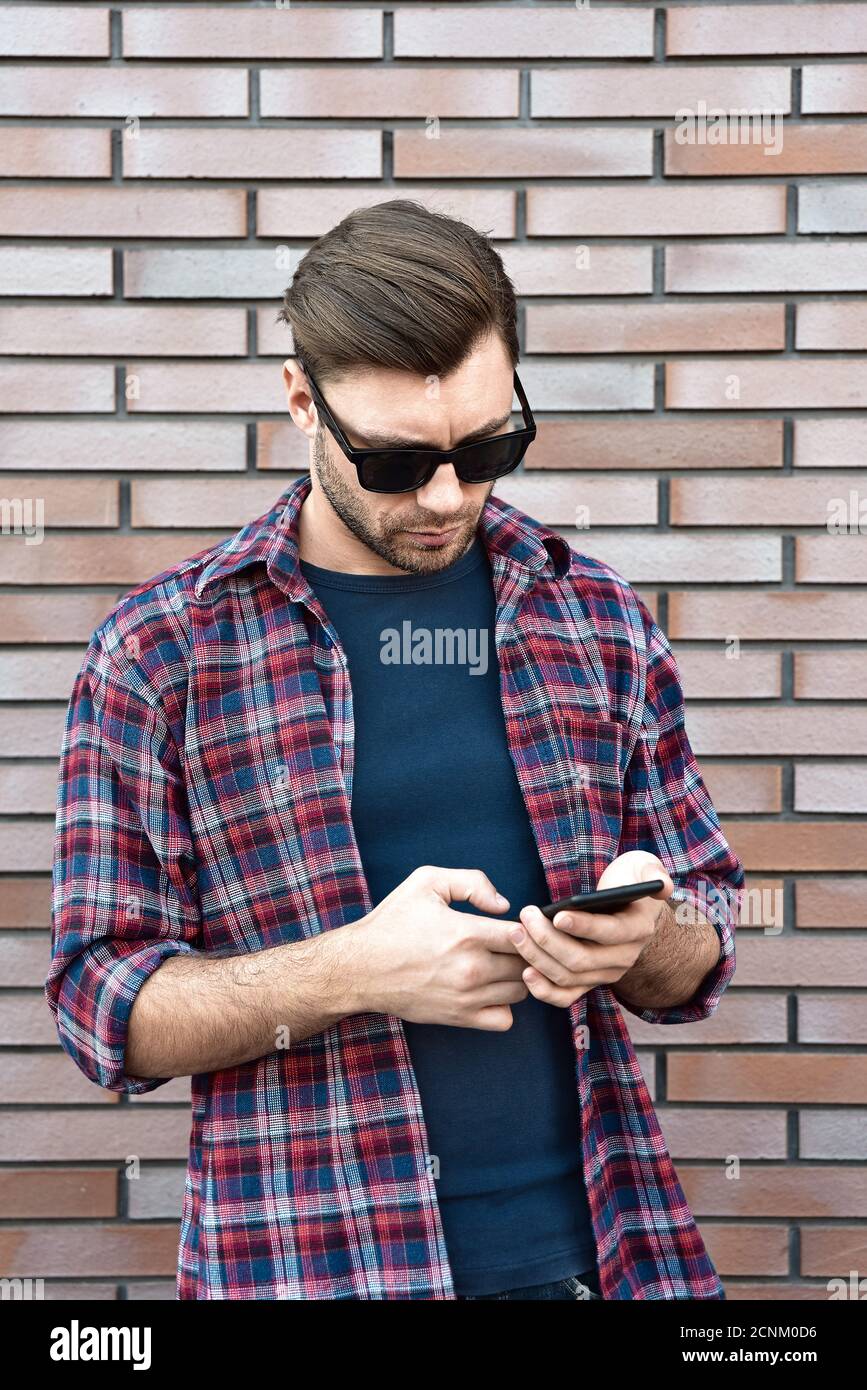 Saisie d'un message texte. Portrait d'un beau jeune homme sérieux quand il utilise son mobile dans la rue. Banque D'Images