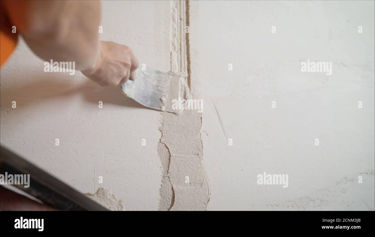 Revêtement décoratif en plâtre. L'homme fait une texture déchiquetée sur le mur à l'aide d'une spatule. Application de plâtre sur le mur Banque D'Images