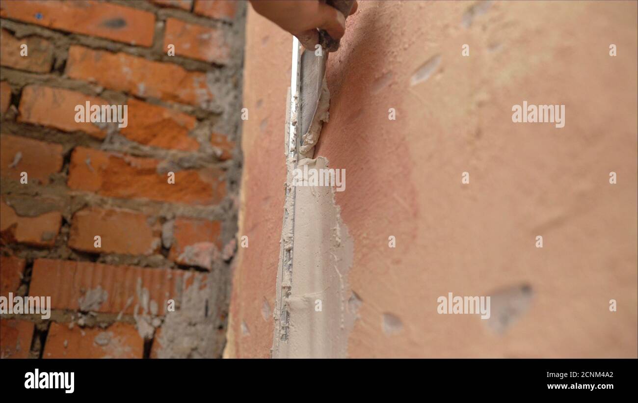 L'utilisation de mortier pour les réparations de mur. Main du travailleur de constructeur utiliser le béton de plâtrage de truelle au mur Banque D'Images