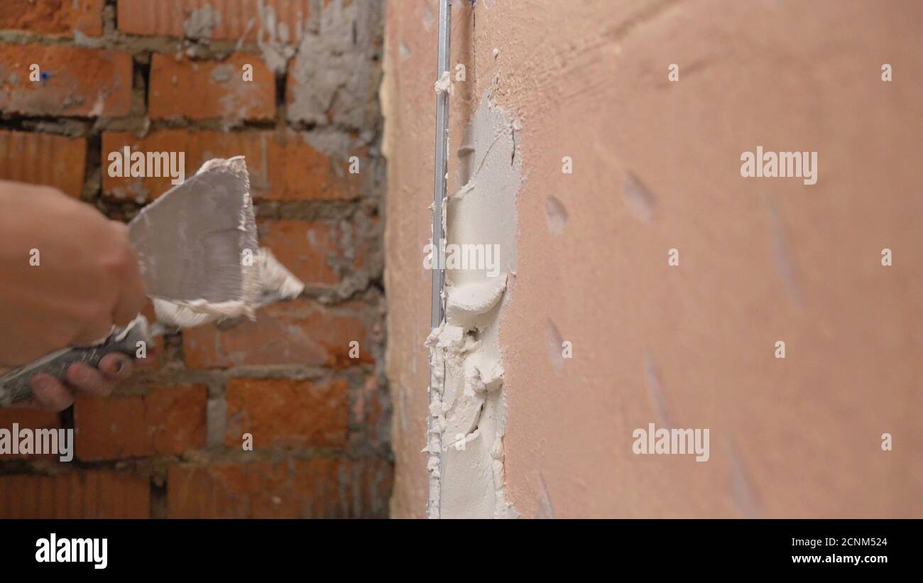 Revêtement décoratif en plâtre. L'homme fait une texture déchiquetée sur le mur à l'aide d'une spatule. Application de plâtre sur le mur Banque D'Images