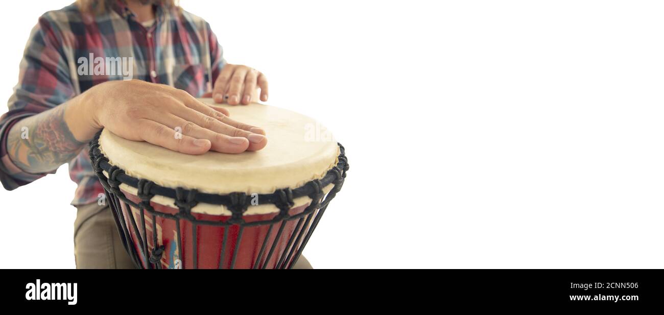 L'homme joue à la percussion ethnique drum darbuka, musicien de gros plan  isolé sur fond blanc de studio. Mains mâles tapotant djembe, bongo en rythme.  Instruments de musique faits main, son de