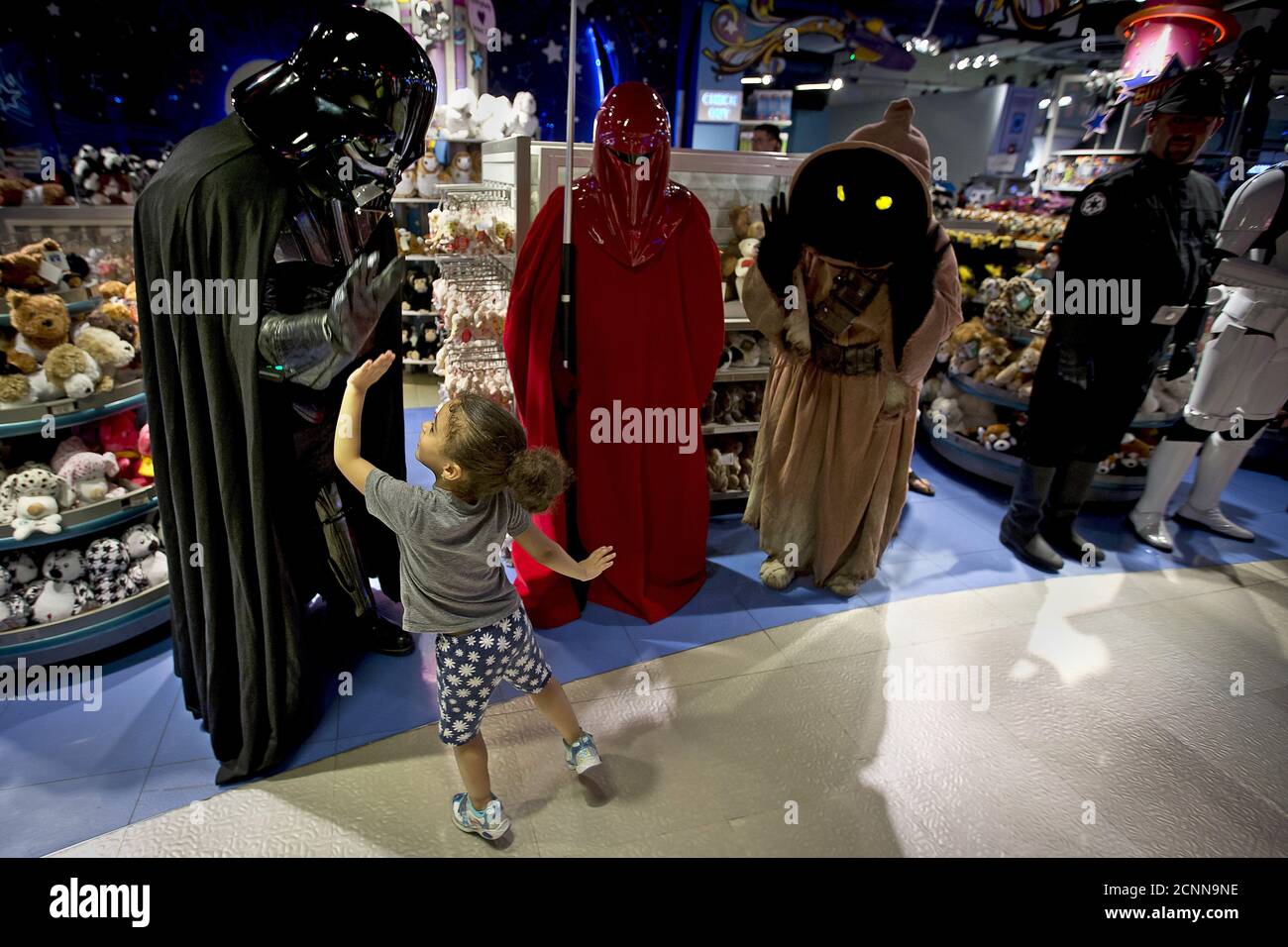 Un homme habillé comme Darth Vader de la haute 'Star Wars' five un enfant  alors que les gens arrivent pour acheter des jouets qui ont été mis en  vente à minuit avant