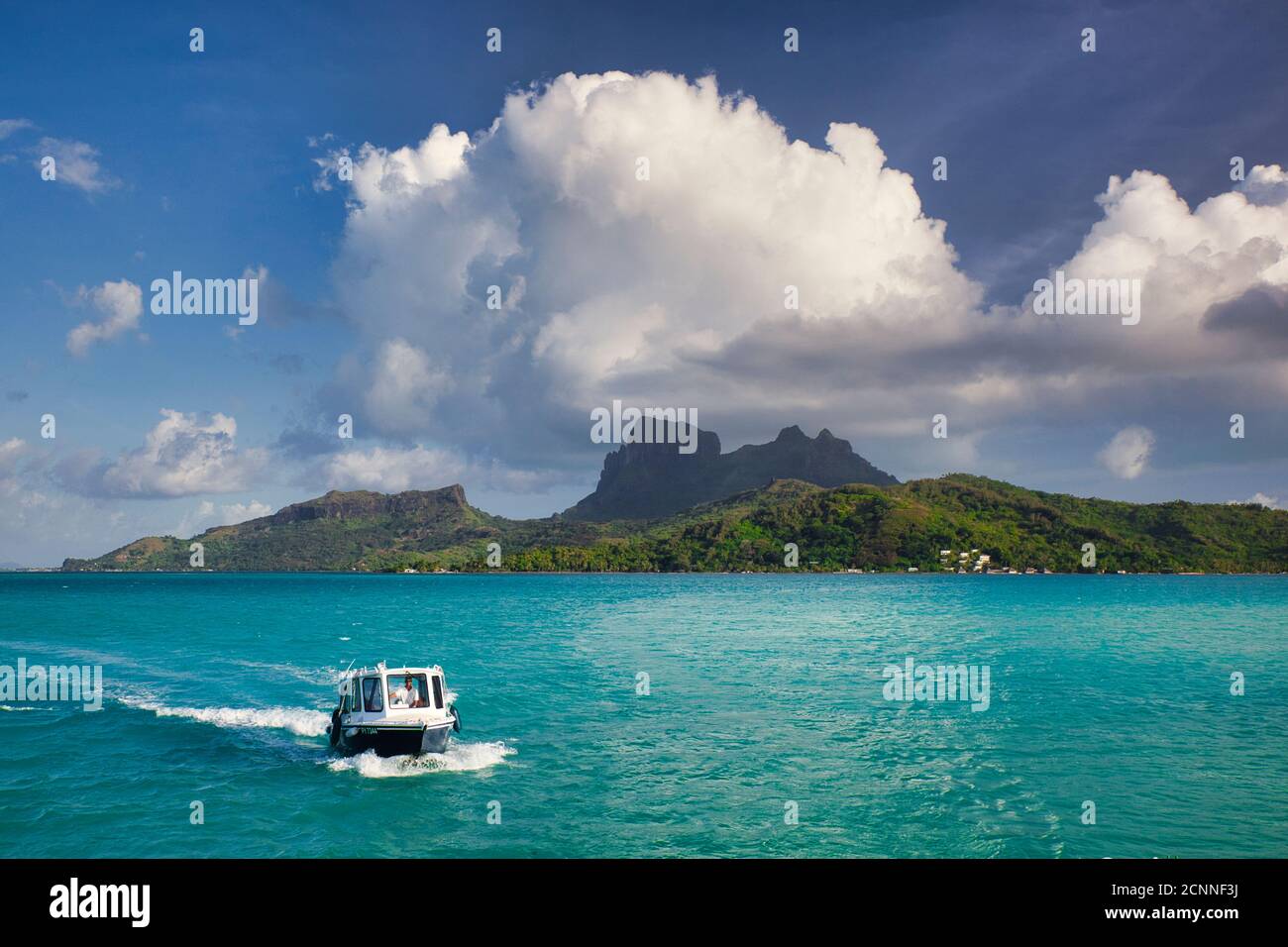 Vue sur la mer avec petit bateau en premier plan, de l'île Bora Bora avec le Mont Otemanu au centre avec ciel bleu et nuage blanc, Polynésie française Banque D'Images