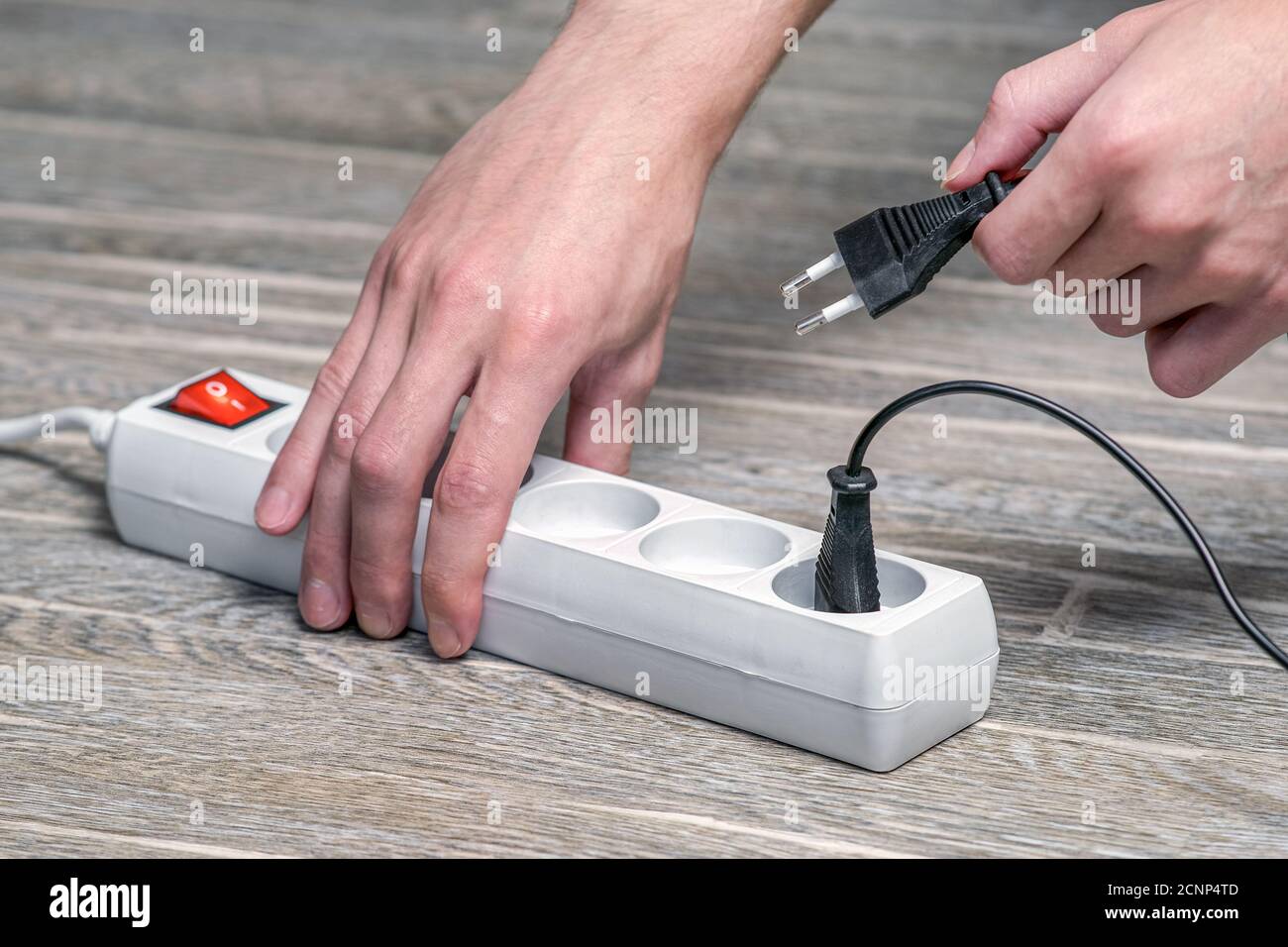 L'hôtesse tient dans sa main une rallonge électrique à l'aide d'un fusible, puis branchez l'appareil sur la prise Banque D'Images