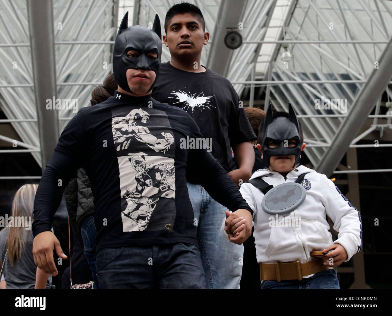 A man walks with son wearing Batman masks as they wait for a midnight  premiere of 
