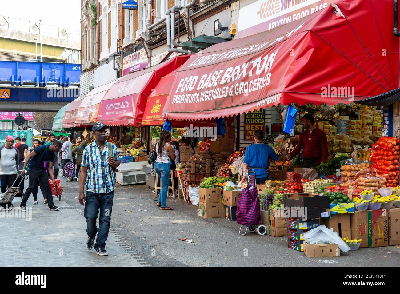 Légumes traditionnels avec des produits de fabrication sur l'affichage et les clients sur Electric Avenue, Brixton, Londres, Angleterre, Royaume-Uni Banque D'Images