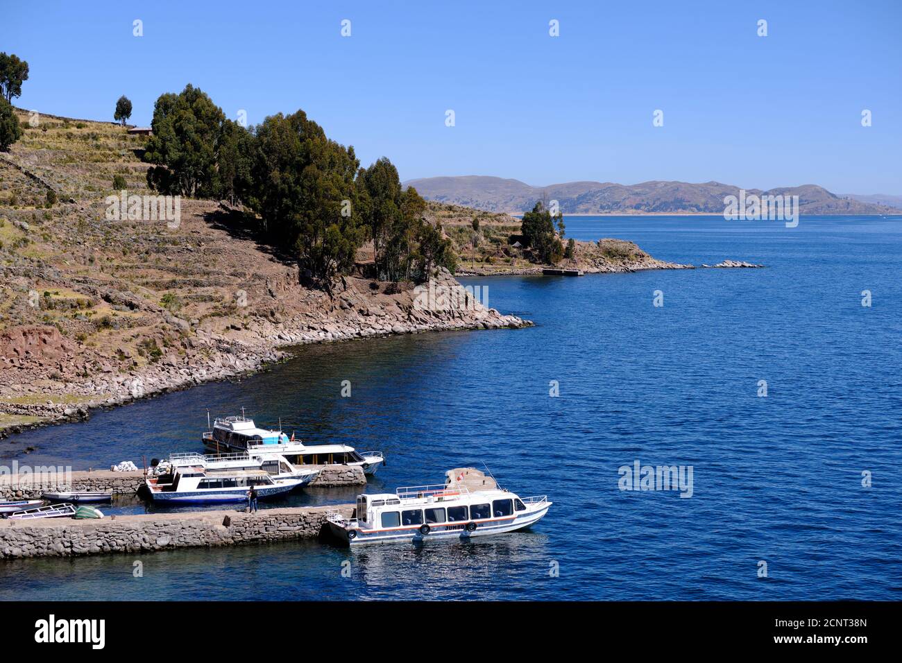 Quatre bateaux de croisière amarrés sur des jetées à l'île de Taquile, au lac Titicaca, au Pérou Banque D'Images