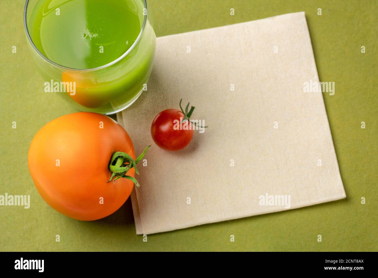 une tasse de verre de jus de concombre frais fait maison avec des tomates fraîches sur une serviette avec un espace de copie, concept de saine alimentation Banque D'Images