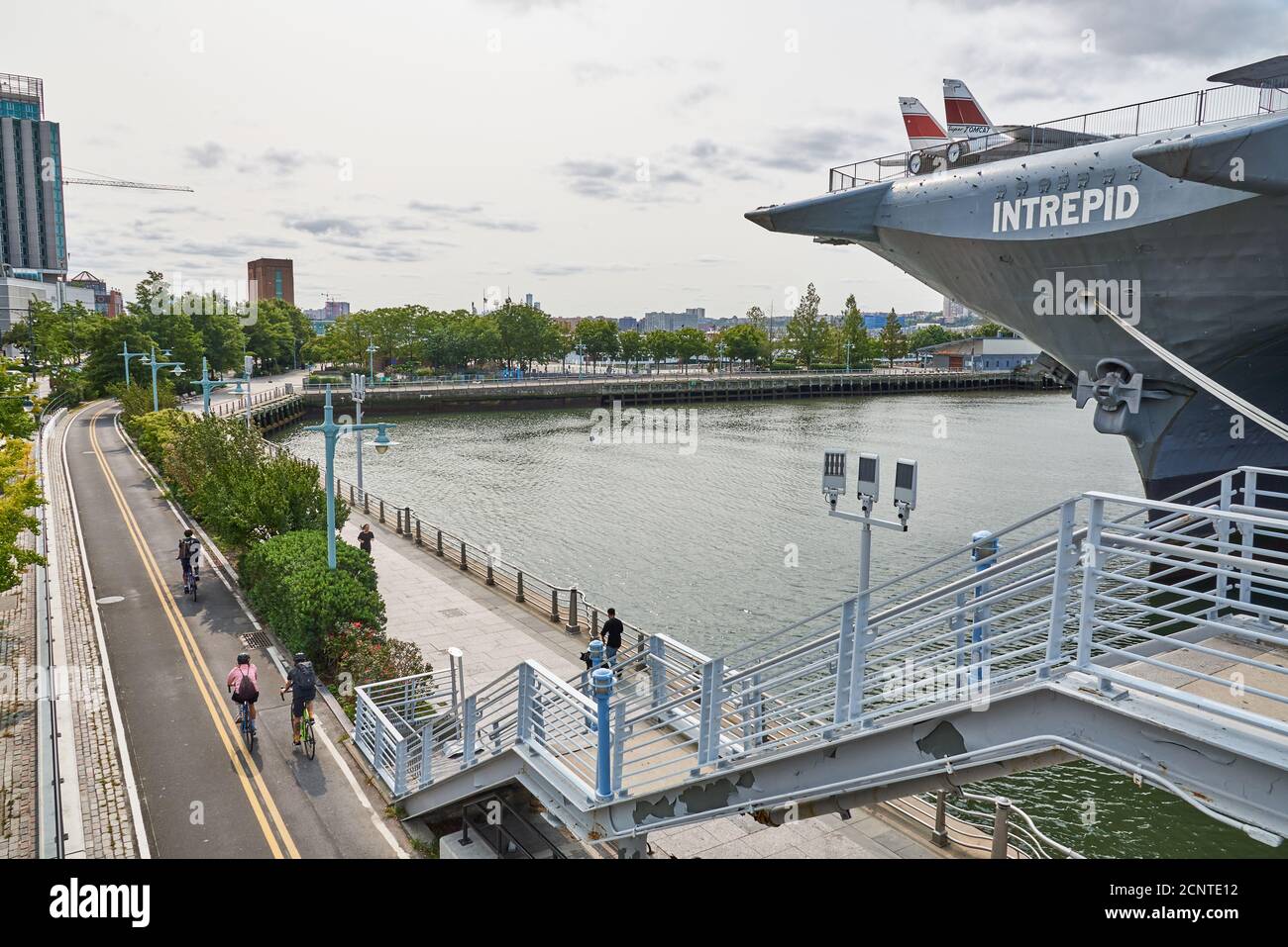 La piste cyclable du parc de l'Hudson avec le porte-avions Intrepid sur la rive de l'Hudson à Midtown Manhattan, New York Banque D'Images