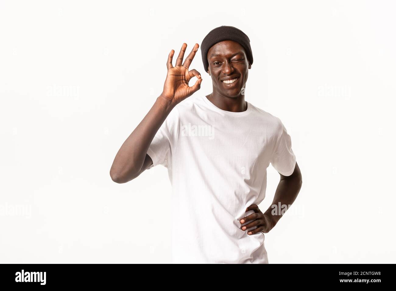 Portrait d'un gars cool afro-américain confiant et optimiste dans le bonnet, assurer tous les bons, en se vriller dans l'approbation et en montrant le geste correct, garantir la qualité Banque D'Images