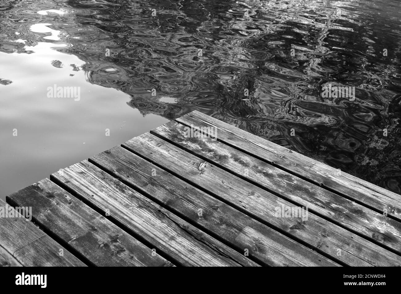 Prise de vue en niveaux de gris d'un quai en bois sur un lac Banque D'Images