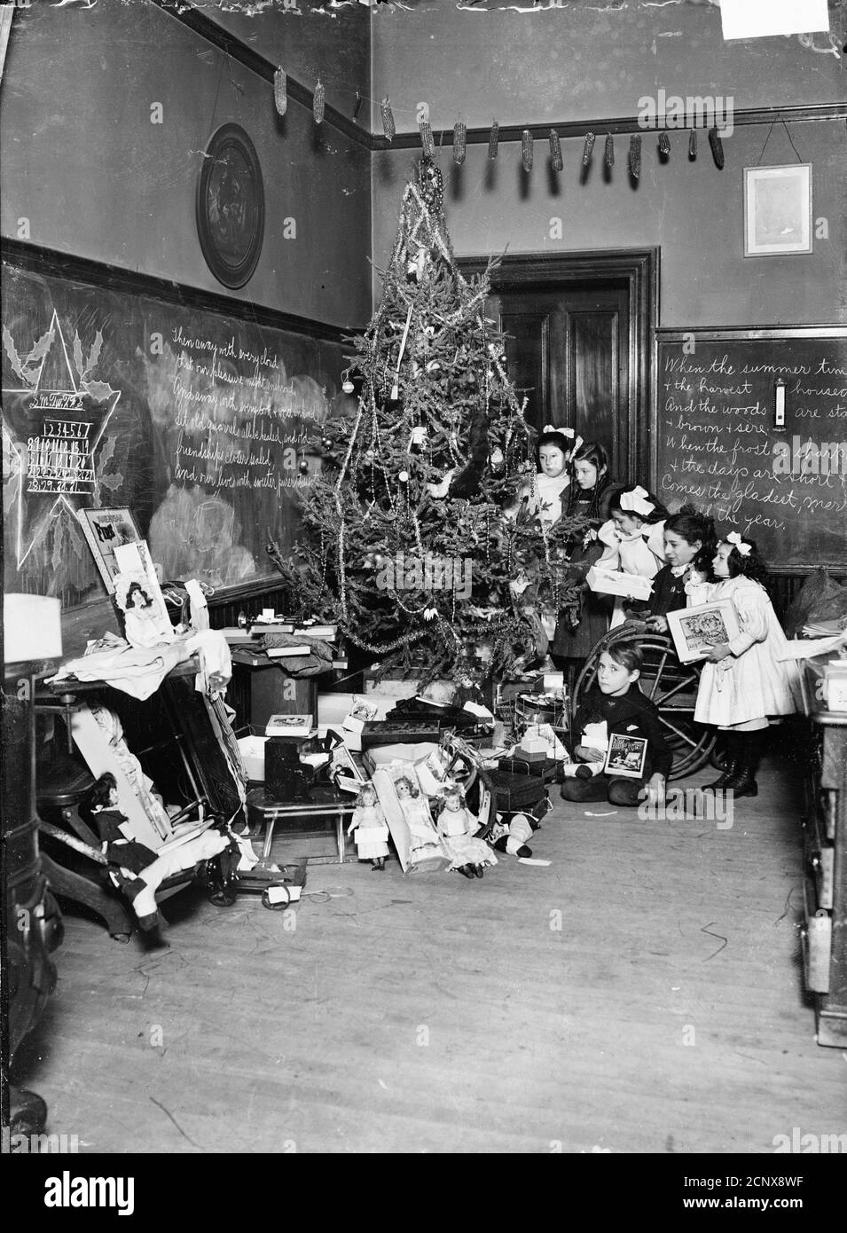 Enfants handicapés tenant des cadeaux tout en étant rassemblés près d'un arbre de Noël entouré de cadeaux dans une salle d'école à Chicago, Illinois, 1905. Banque D'Images