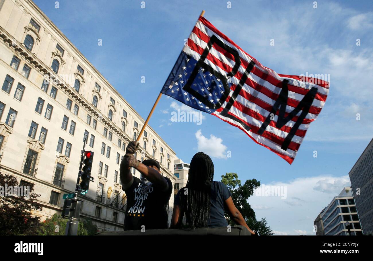 Un démonstrateur défait le drapeau américain à l'envers avec les lettres « BLM » à la « Black Lives Matter Plaza », près de la Maison Blanche, lors d'une protestation contre les inégalités raciales à la suite de la mort de George Floyd, détenu par la police de Minneapolis, à Washington, aux États-Unis, le 6 juin 2020. REUTERS/Jim Bourg Banque D'Images