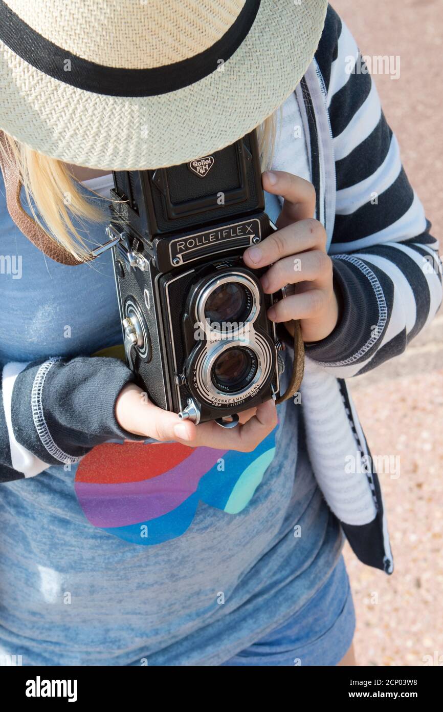 Une jeune fille adulte dans un chapeau de paille d'en haut Utilise un appareil photo reflex numérique Rolleiflex vintage pour cadrer un sujet dans le viseur Banque D'Images