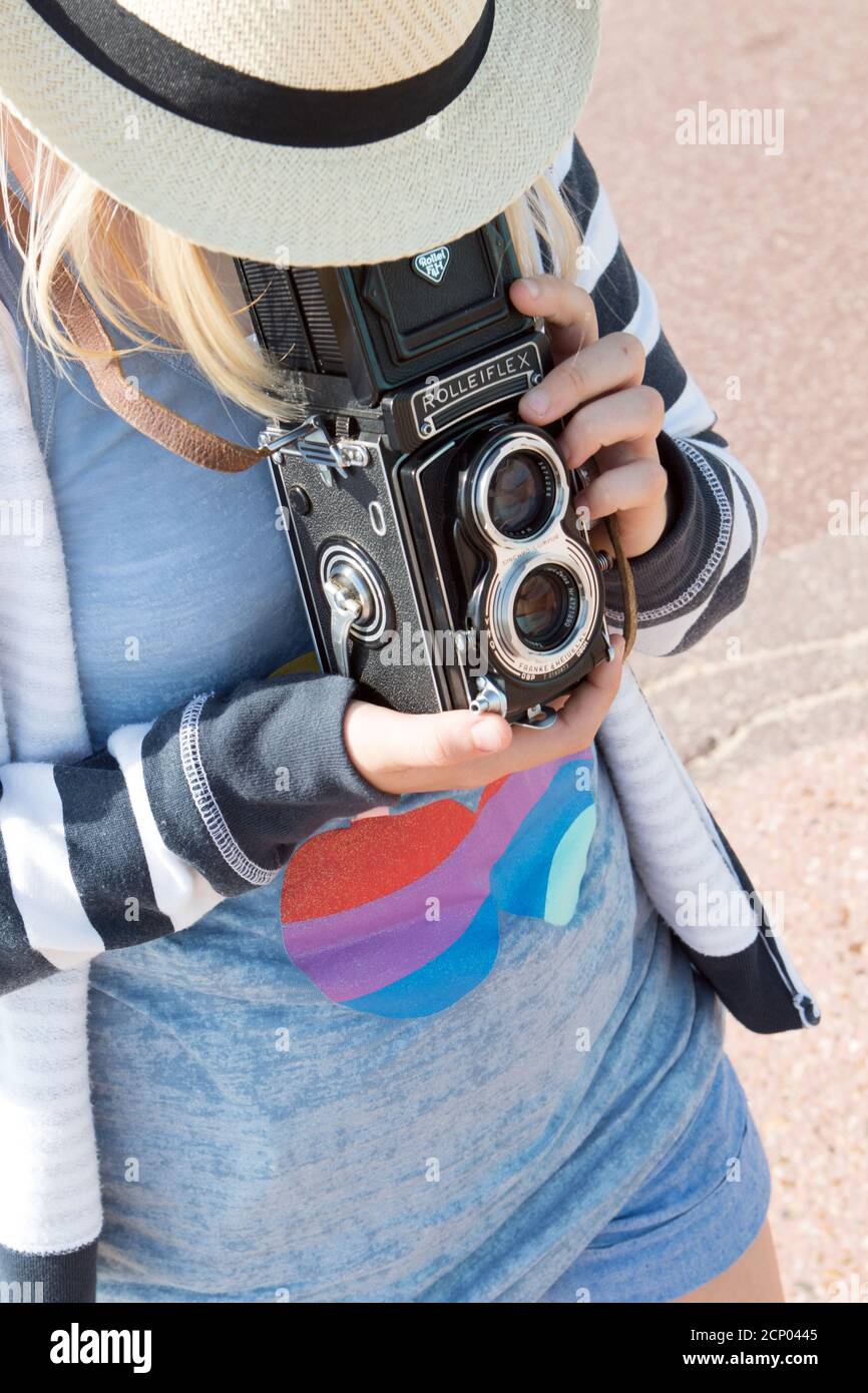 Une jeune fille adulte dans un chapeau de paille d'en haut Utilise un appareil photo reflex numérique Rolleiflex vintage pour cadrer un sujet dans le viseur Banque D'Images