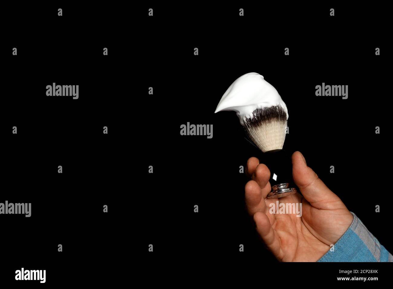 homme tenant la brosse et la mousse dans les mains pour se raser arrière-plan noir Banque D'Images