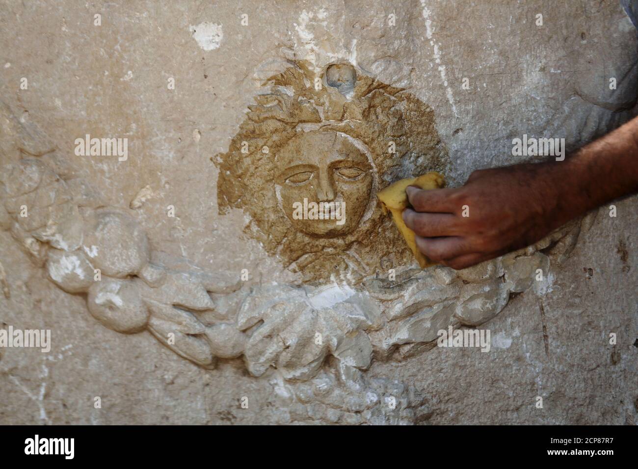 Un employé de l'Autorité des Antiquités d'Israël nettoie une gravure sur un sarcophage tel qu'il est exposé pour les médias près de la ville israélienne de Beit Shemesh le 3 septembre 2015. L'Autorité des Antiquités d'Israël (IAA) a déclaré mercredi que leurs inspecteurs et policiers israéliens ont révélé le rare sarcophage après qu'il ait été dissimulé par des entrepreneurs, qui l'ont endommagé lorsqu'ils l'ont retiré du sol à tort et l'ont caché pendant les travaux de construction dans la ville d'Ashkelon, dans le sud du pays. Le sarcophage calcaire unique de 1800 ans, sculpté de tous les côtés, pèse environ 2 tonnes et est de 2.5 m lo Banque D'Images