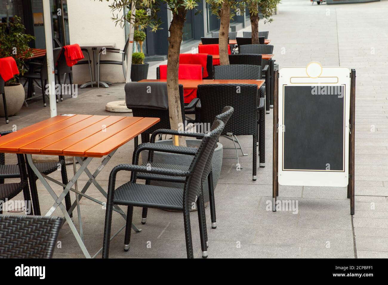 Tables vides d'un café de rue. Tableau noir à côté du café. Banque D'Images