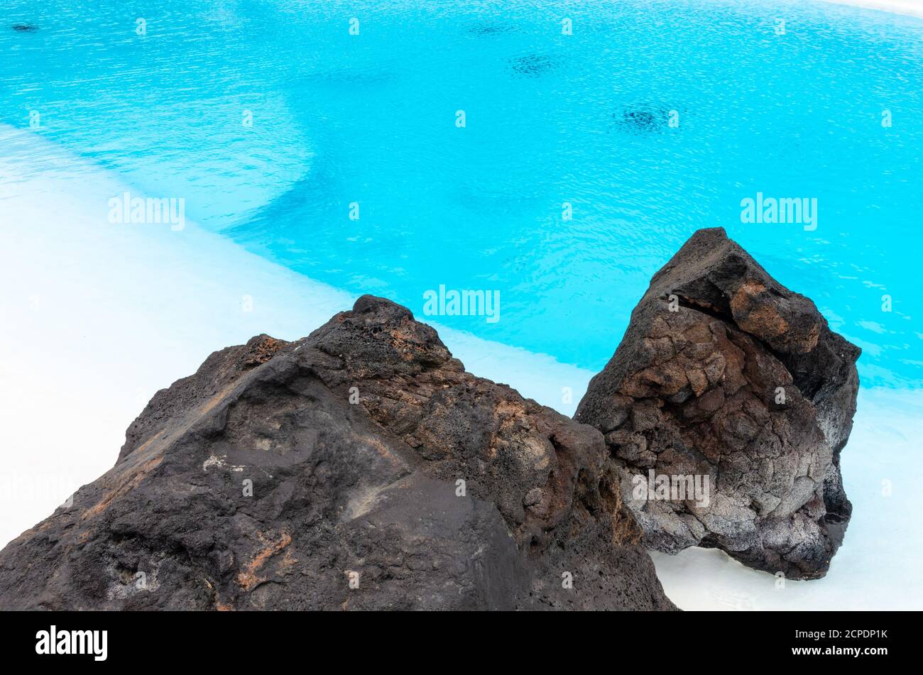 Une piscine avec de l'eau turquoise et des roches volcaniques noires pour décoration Banque D'Images