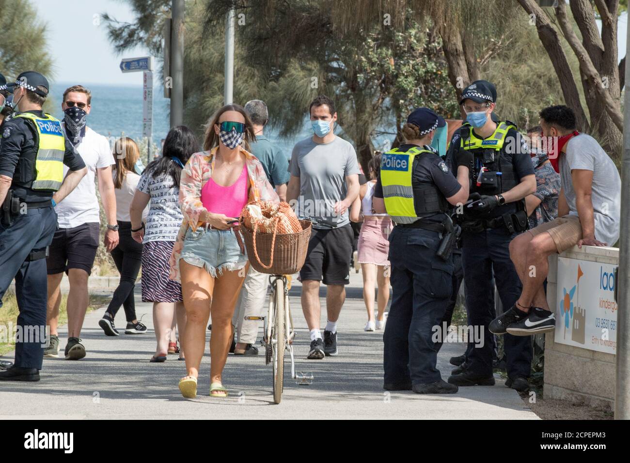 Melbourne, Australie. 19 septembre 2020. les amateurs de plage marchent devant un manifestant qui est interrogé et qui a été condamné à une amende de 1600 $ par les policiers de Victoria à Elwood Beach après une manifestation anti-masque et anti-verrouillage qui a commencé à Elsternwick Park, Melbourne, Australie. Crédit : Michael Currie/Alay Live News Banque D'Images
