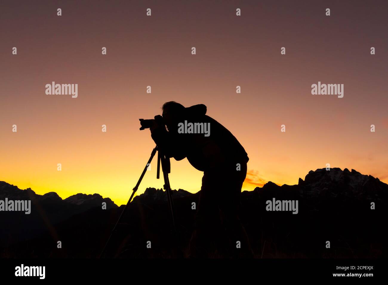 Silhouette de photographe à prendre des photos en montagne au lever du soleil Banque D'Images