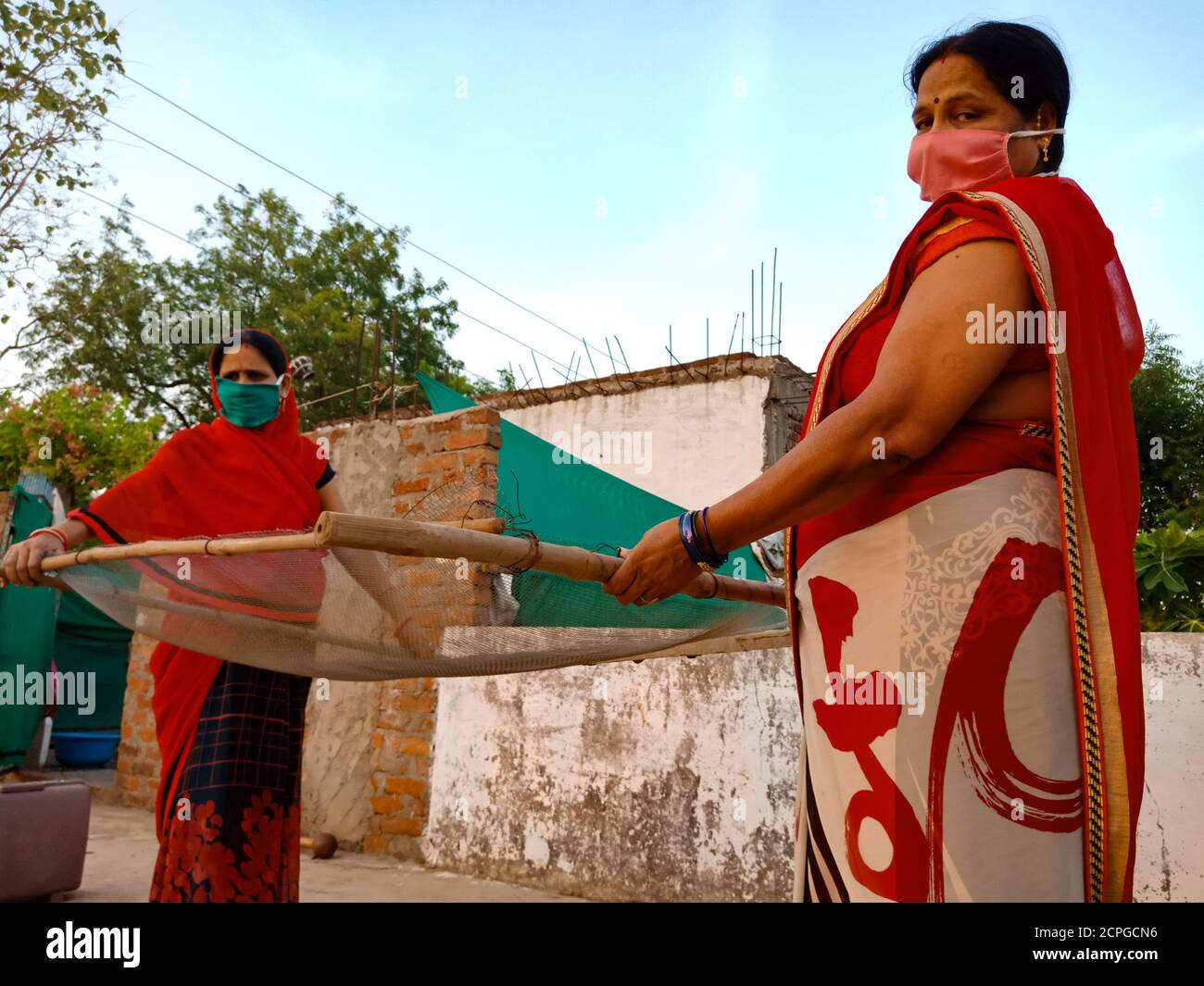 DISTRICT KATNI, INDE - 21 MAI 2020 : deux femmes indiennes de village portant un masque pour la protection du virus corona Holded Sand filter construction outils à Banque D'Images