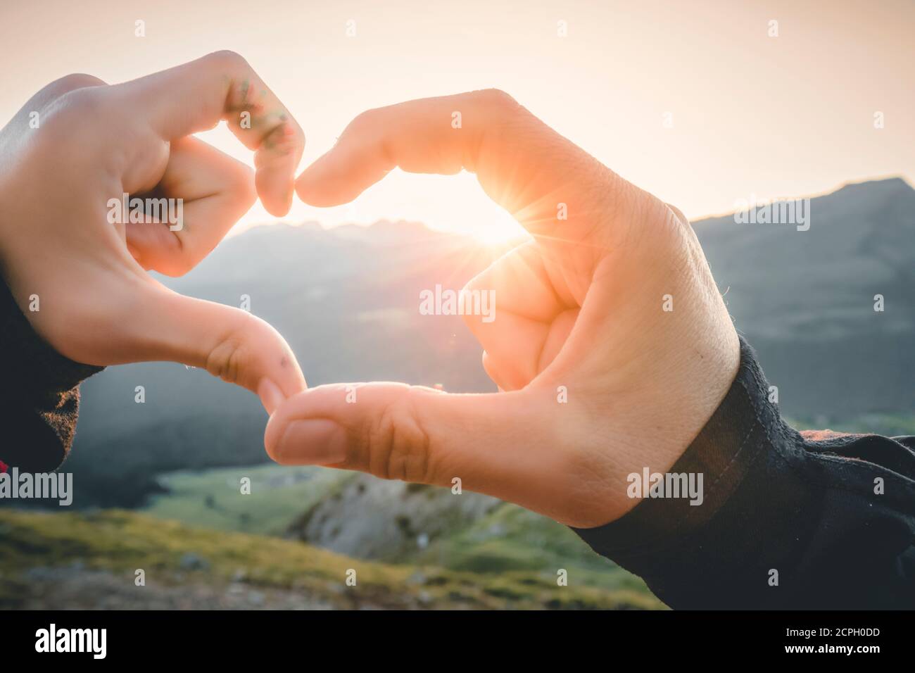 mère et fille, femme et fille se joignent aux mains pour créer la forme du cœur avec le soleil couchant Banque D'Images