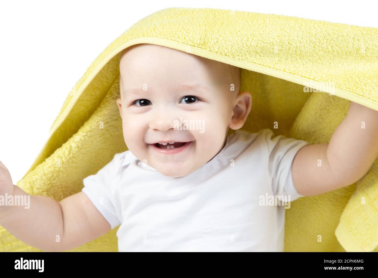 Rire bébé de onze mois sous une serviette jaune Banque D'Images