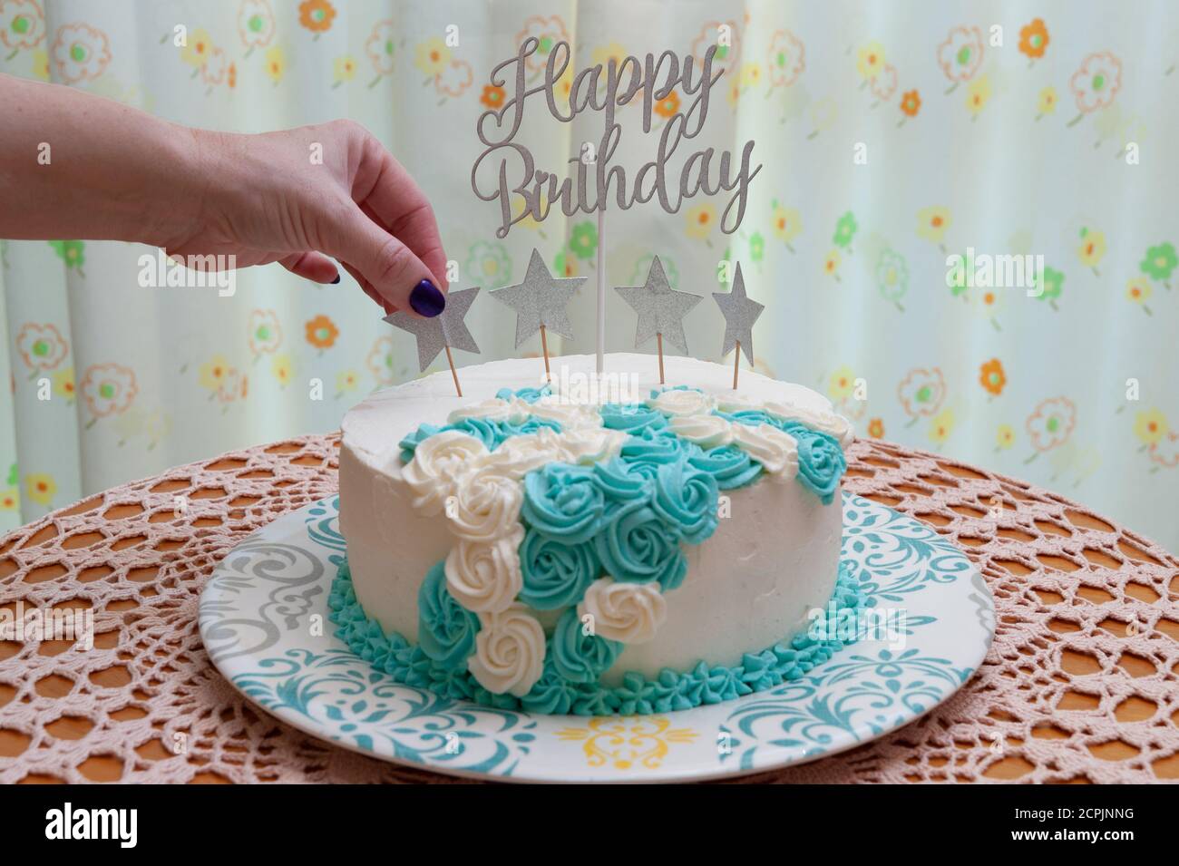 Gateau D Anniversaire Decore De Glacage Blanc Et Bleu Femme A La Main Mettant Une Etoile D Ornement Fond De Rideau Fleuri Vue Avant Gros Plan Photo Stock Alamy