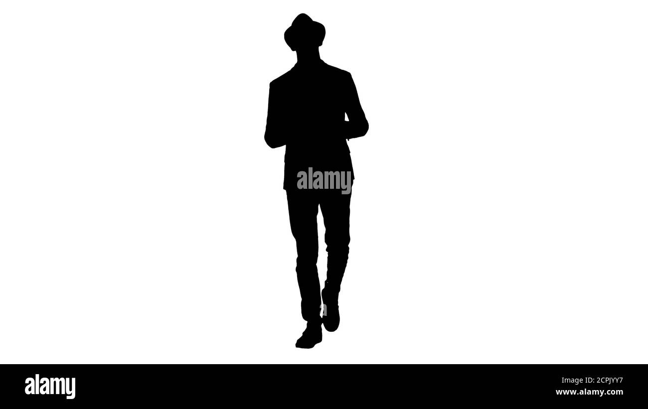 Silhouette tendance élégant positif gai homme portant une chemise et un chapeau de soleil à la marche et à la conversation avec l'appareil photo. Banque D'Images