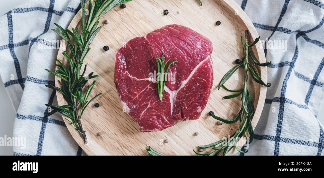 Viande crue, steak de boeuf, sur bois avec romarin Banque D'Images