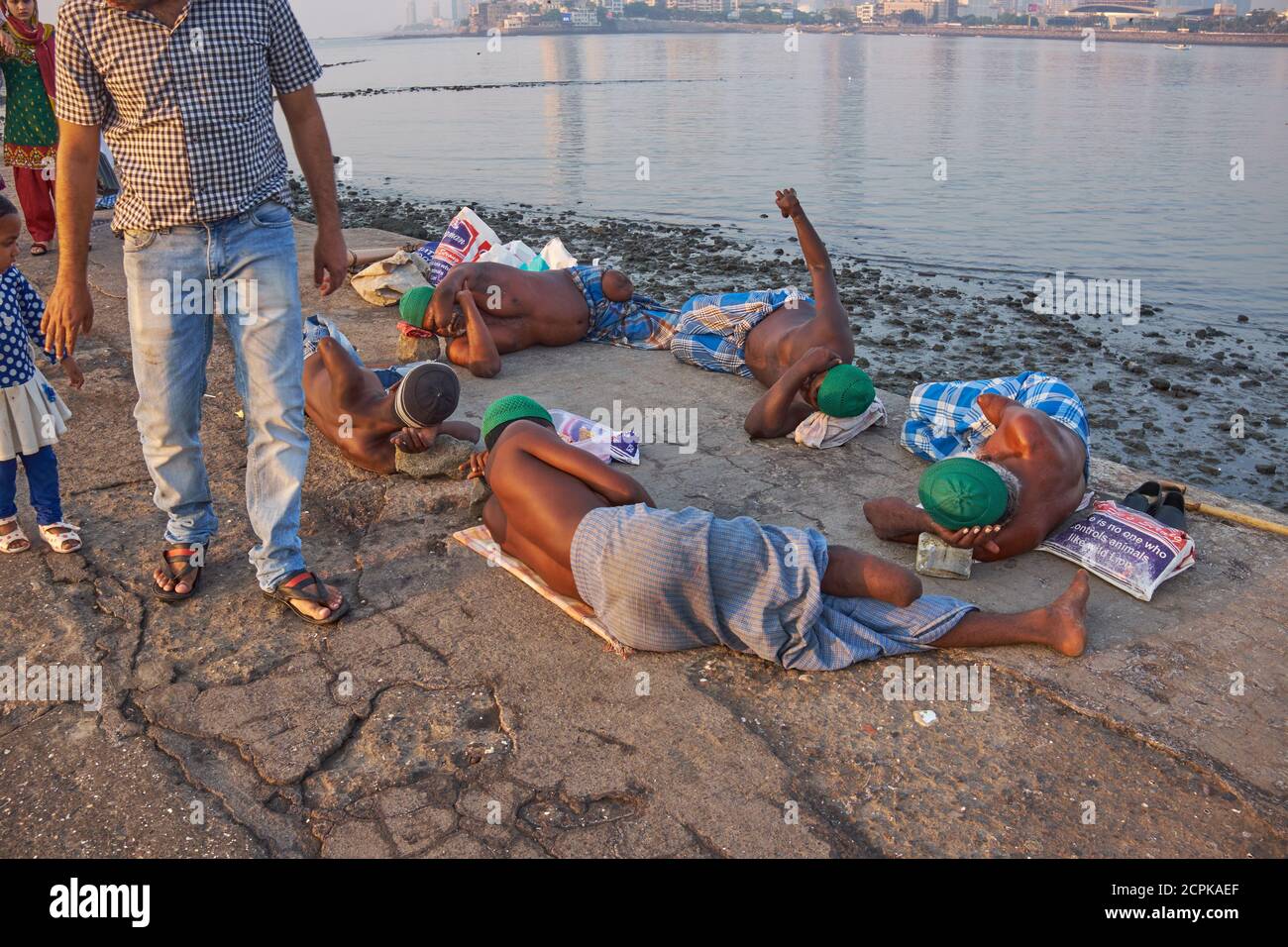 Mendiants aux membres amputés ou souffrant de lèpre sur la passerelle menant à la mosquée et à la Dargah de Haji Ali à Worli, Mumbai, en Inde, alors qu'une famille passe à côté Banque D'Images