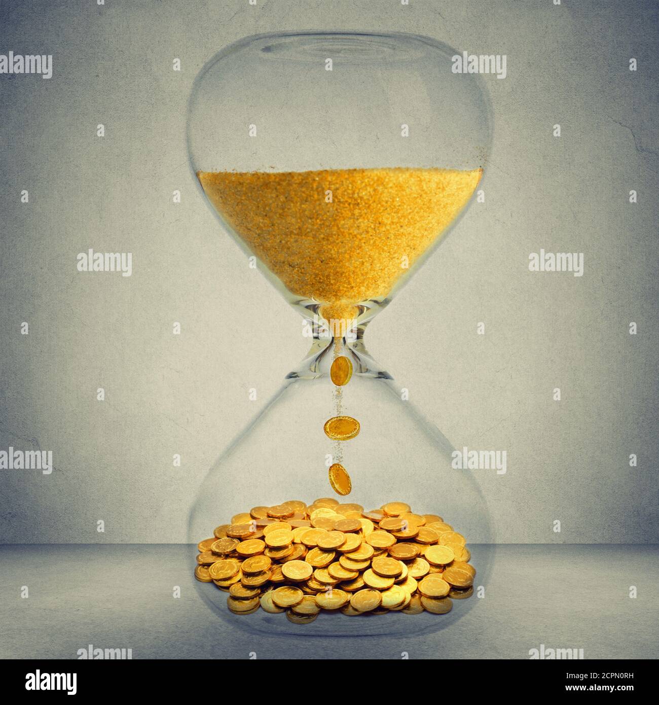 Le temps, c'est le concept d'opportunité financière de l'argent. Horloge de sable avec poussière d'or et pièces isolées sur fond de mur gris Banque D'Images