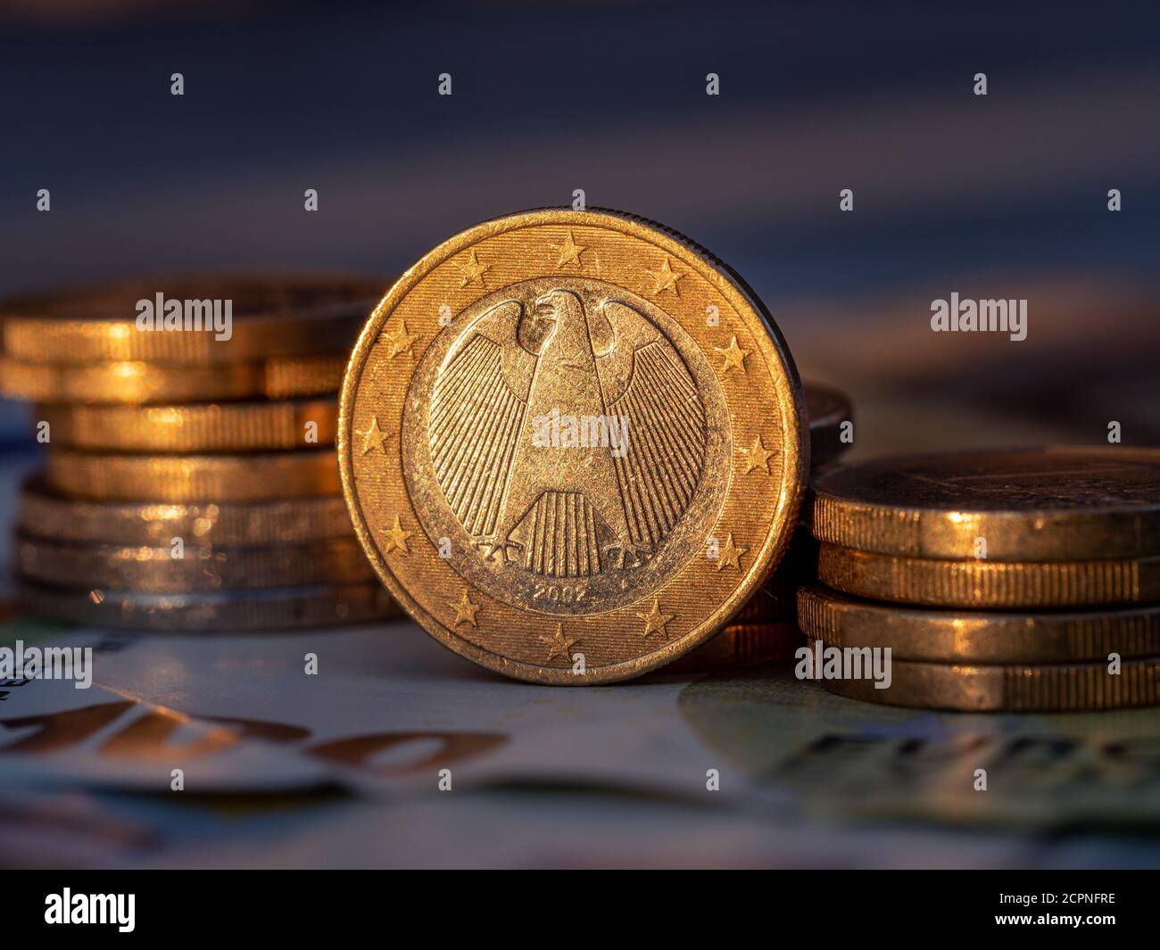Gros plan sur une pièce de monnaie allemande d'un euro avec des piles de pièces de monnaie d'un centiret d'euro. Banque D'Images